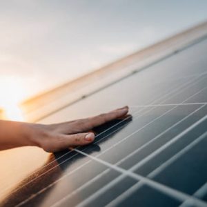 Close-up of human hand touching solar panel during Sunset